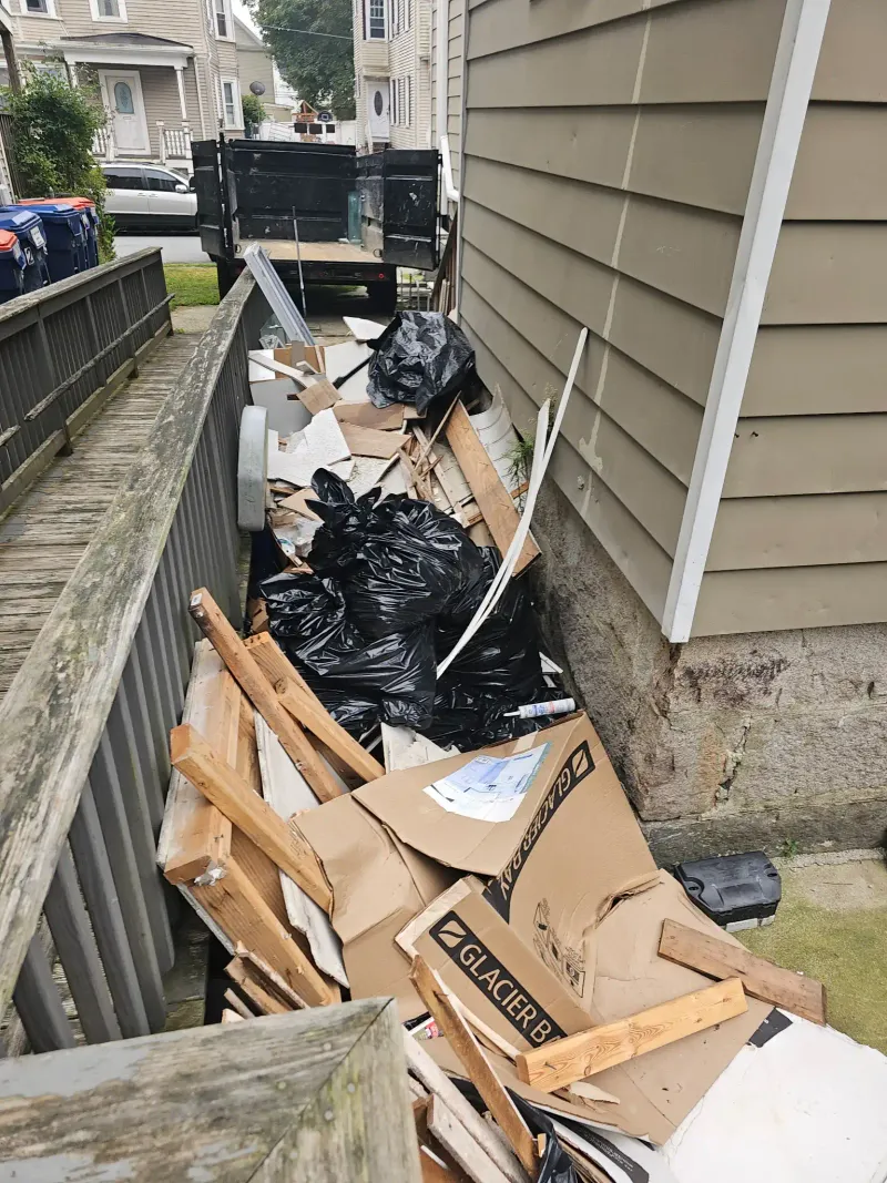 Driveway filled with cardboard boxes and trash bags before junk removal near Barnstable