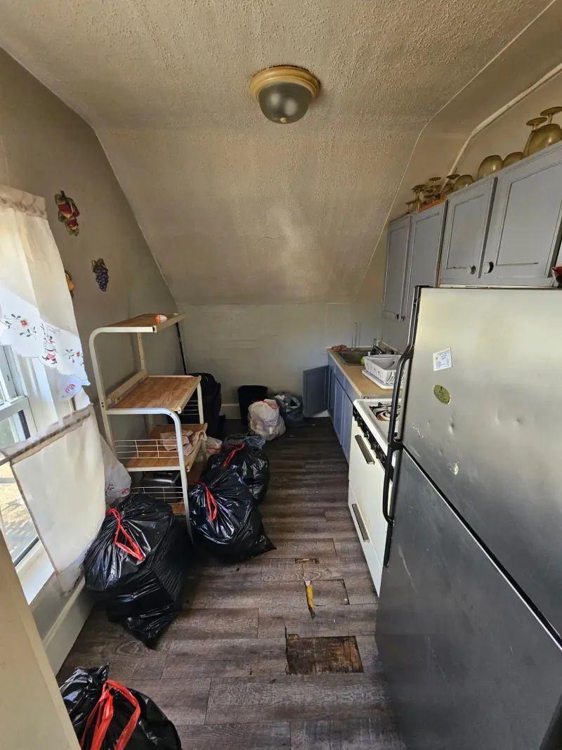 Kitchen cleanout with bagged debris and old appliances near Barnstable